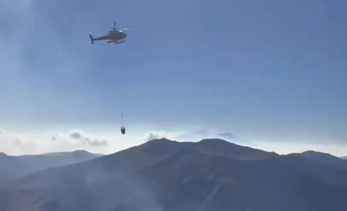 Helikopter melakukan water boombing di kawasan Gunung Bromo, terbang di atas lereng pegunungan untuk menjatuhkan air.