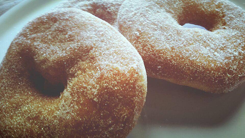 Sejumlah graffe napoletane berbentuk cincin, donat goreng khas Napoli, tersaji di piring dengan taburan gula.