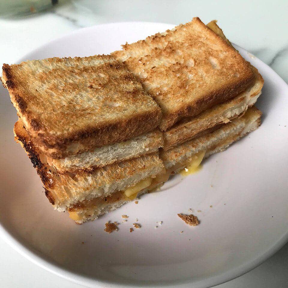 Sepiring kaya toast berupa roti panggang isi selai kaya berwarna cokelat keemasan di atas piring putih.