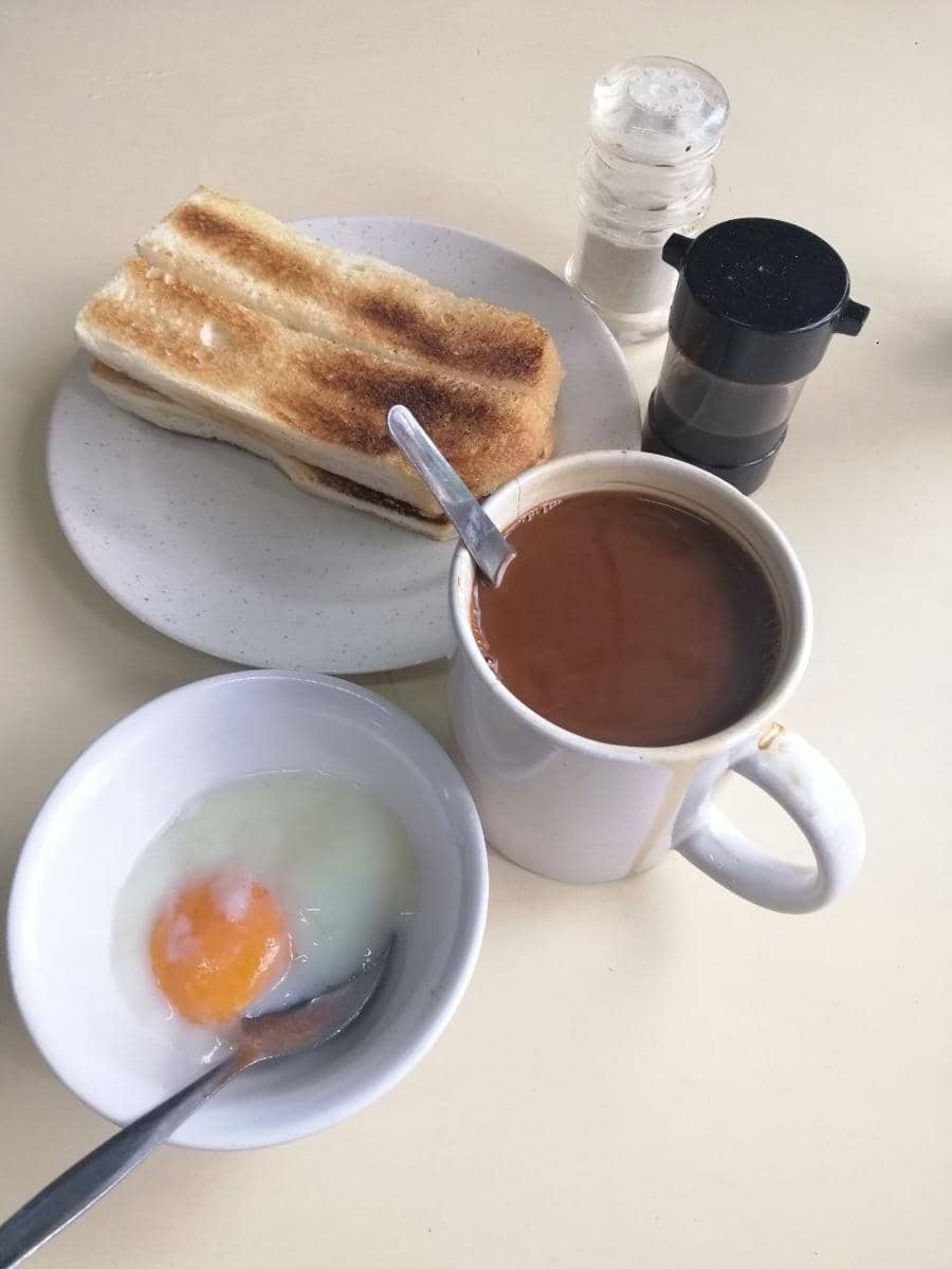Ilustrasi kaya toast berupa roti panggang berlapis selai kaya, disajikan di atas piring putih dengan potongan mentega.