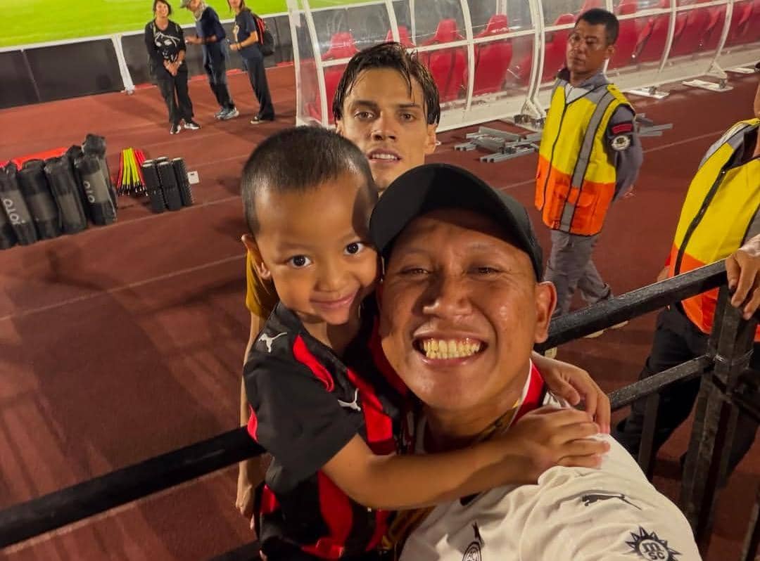 Oki Rengga dan Arthur berpose bersama pemain AC Milan di lapangan latihan dengan mengenakan pakaian olahraga.