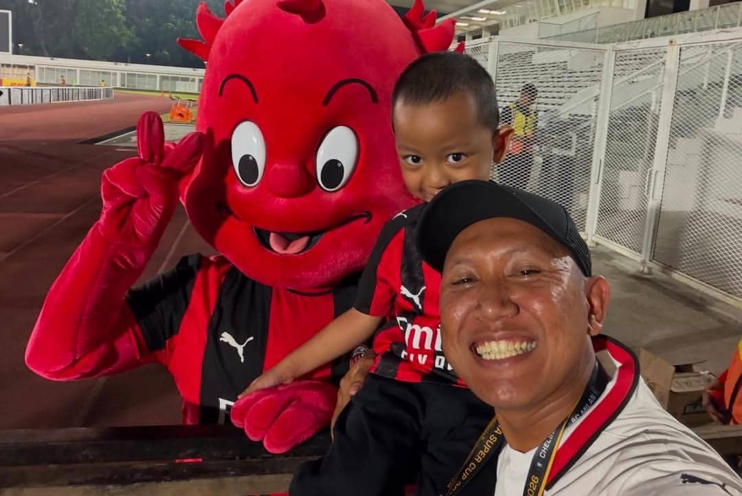 Oki Rengga dan Arthur berpose bersama sejumlah pemain AC Milan di lapangan latihan klub dengan latar rumput.