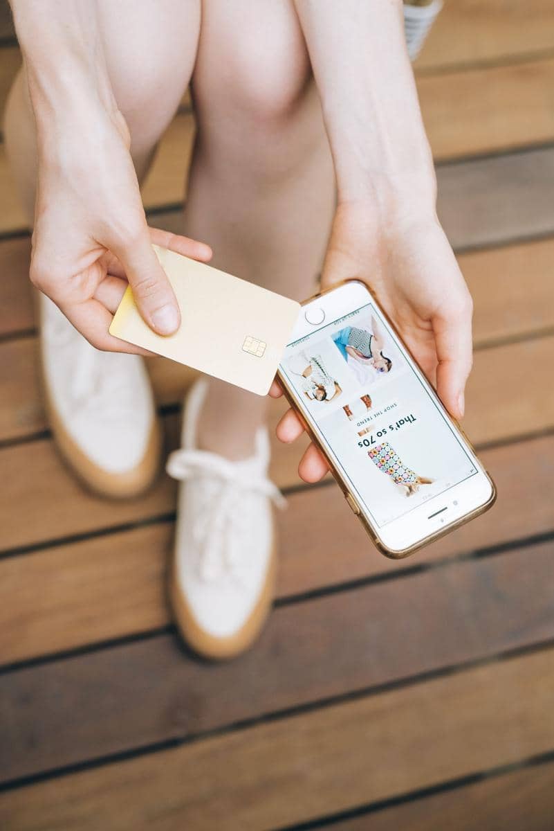 Seseorang menggunakan smartphone dan kartu pembayaran untuk checkout belanja online