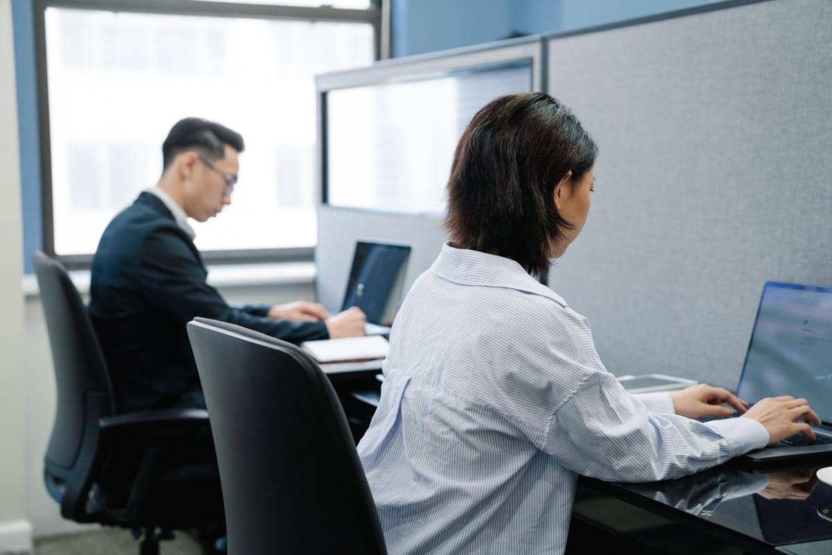 Karyawan yang sedang fokus bekerja dengan laptop di meja kantor.