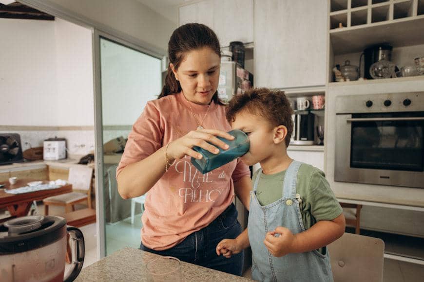 Seorang ibu memberikan minum kepada anaknya dalam ilustrasi tentang perhatian dan pemenuhan kebutuhan anak.