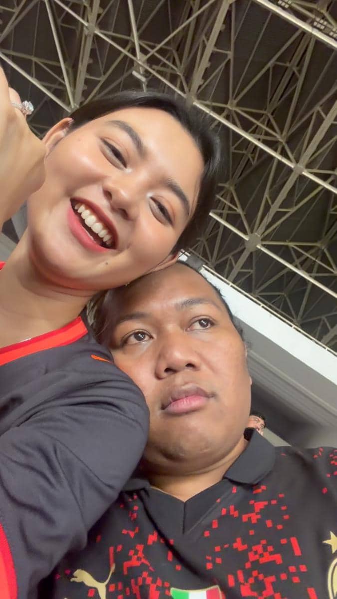 Seorang artis mengenakan atribut AC Milan saat menjadi suporter di GBK dalam suasana pertandingan sepak bola.