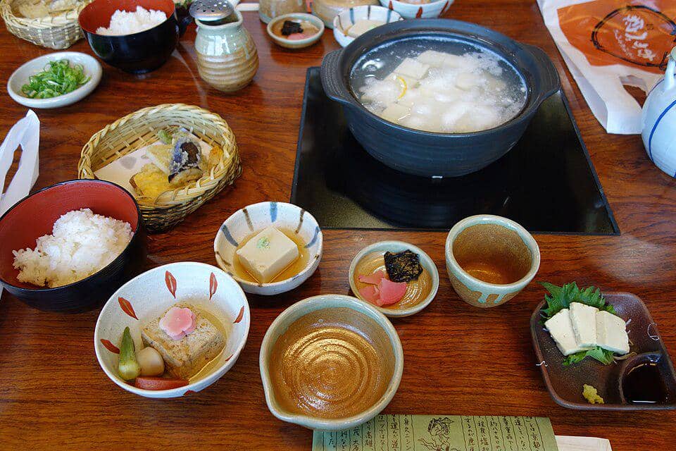 Ilustrasi yudofu, hidangan tahu rebus khas Jepang, disajikan dalam set menu makan siang dengan pelengkap.
