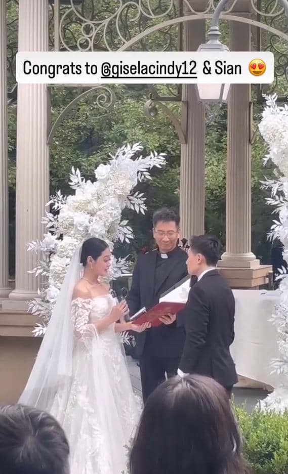 Gisela Cindy dan pasangannya berpose dalam potret pernikahan mengenakan busana pengantin putih yang elegan.