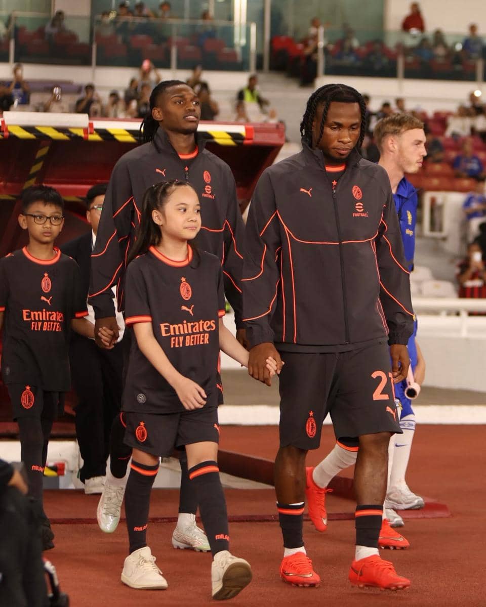 Gempi mengenakan seragam AC Milan sambil menggandeng tangan pemain saat memasuki lapangan Stadion Utama GBK.