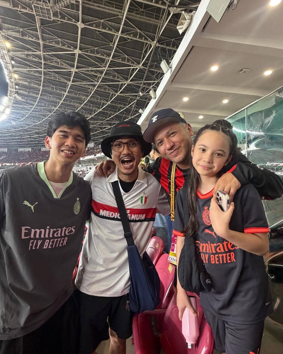 Gempi berjalan sambil menggandeng tangan pemain AC Milan di Stadion GBK saat memasuki lapangan pertandingan.