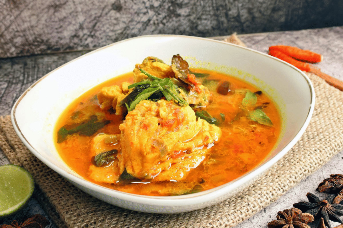 Semangkuk gulai ikan tenggiri khas rumah makan Padang dengan kuah kuning dan potongan ikan berbumbu.