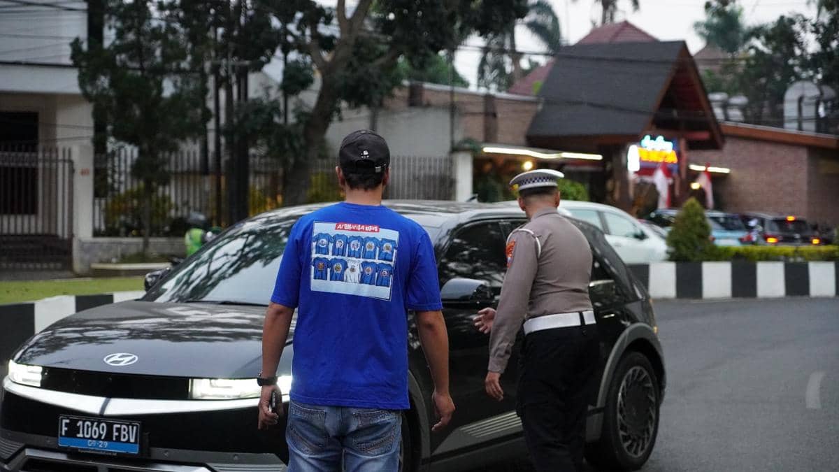Sejumlah Aremania membagikan bunga kepada pengendara di jalan Kota Malang sebagai bagian dari kegiatan bersama.