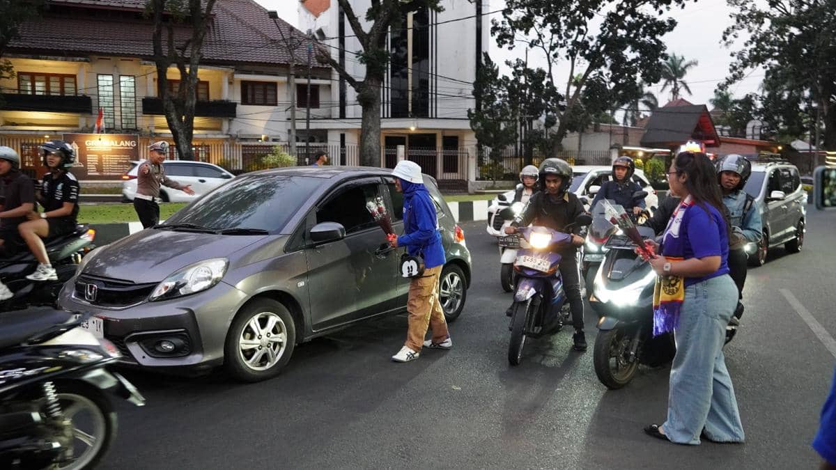 Sejumlah Aremania membagikan bunga kepada pengendara kendaraan di jalanan Kota Malang sebagai aksi damai.