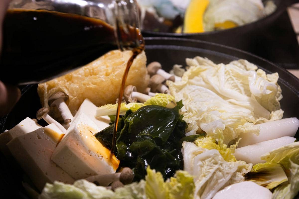 Ilustrasi ttukbaegi doenjang jjigae, sup pasta kedelai khas Korea, disajikan dalam mangkuk tanah liat.