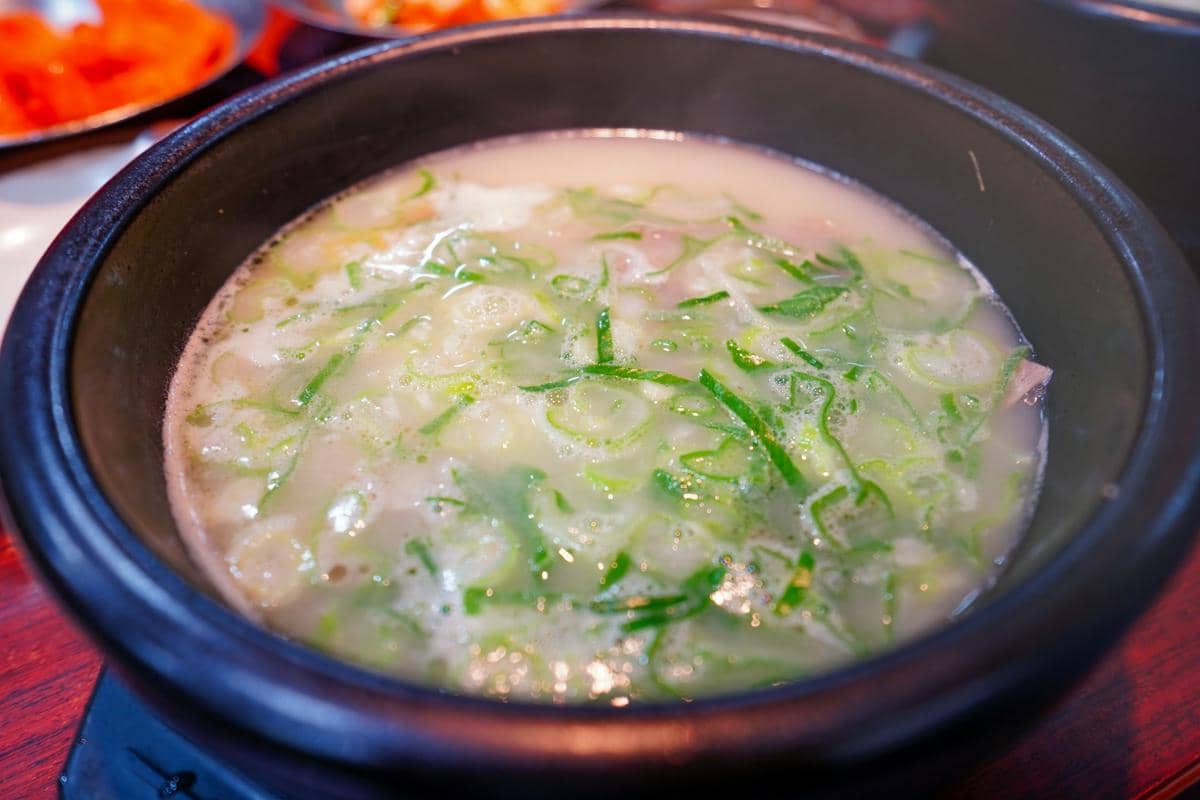 Ilustrasi proses pembuatan ttukbaegi doenjang jjigae, hidangan yang dimasak dan disajikan dalam wadah tradisional.