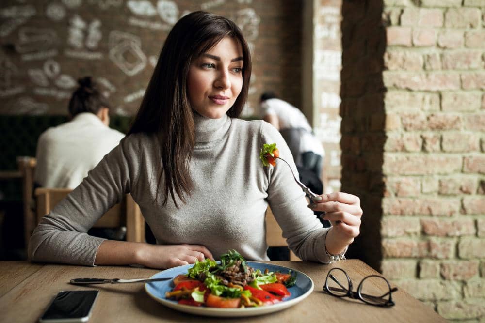 Ilustrasi perempuan sedang makan dengan ekspresi santai, menggambarkan aktivitas menikmati makanan dalam keseharian.