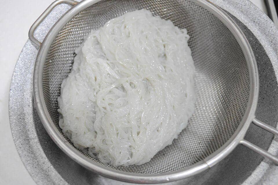 Ilustrasi mi untuk naengmyeon, hidangan mi dingin Korea yang disajikan dalam mangkuk dengan kuah.