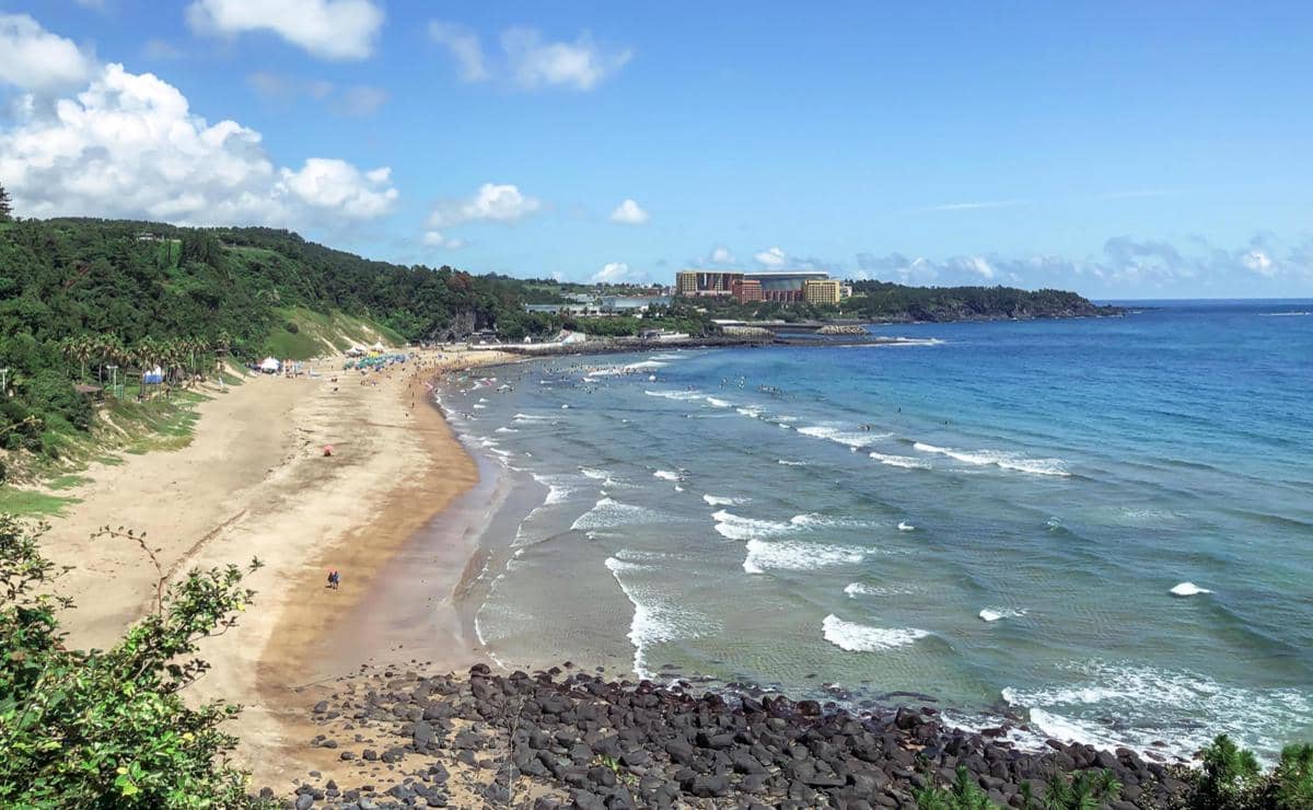 Pemandangan pantai di Pulau Jeju, Korea Selatan, dengan laut dan garis pantai di bawah langit cerah.