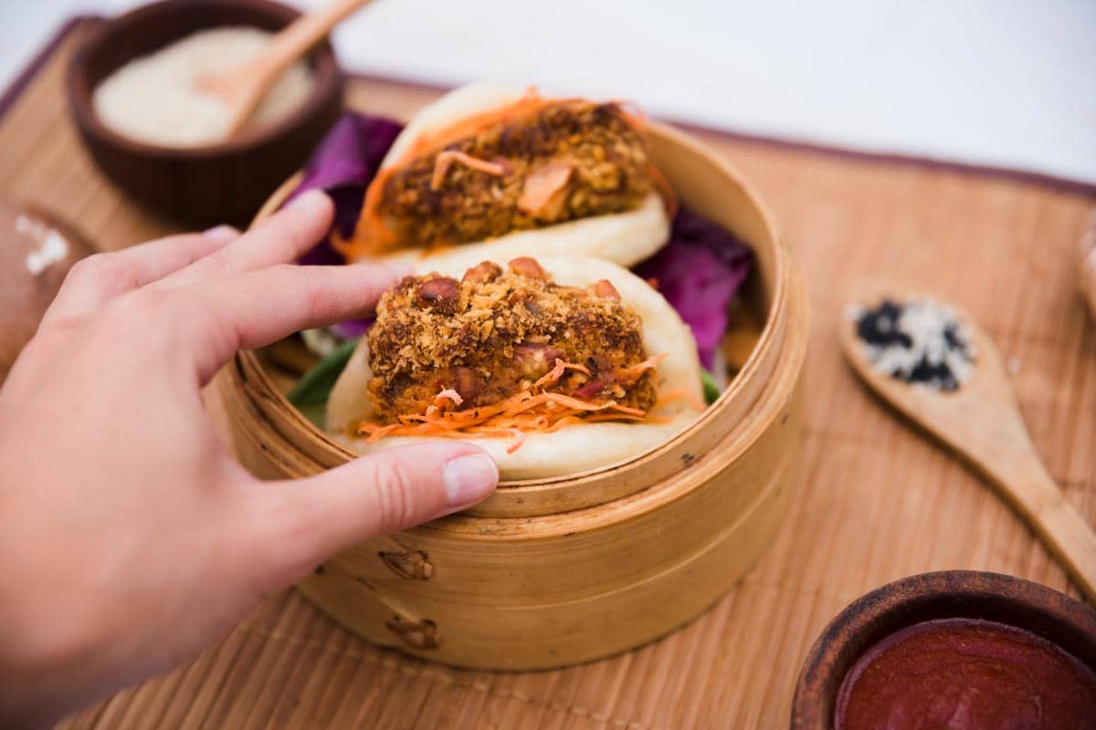 Ilustrasi gua bao, roti kukus lipat khas Taiwan berisi daging, sayuran, dan saus, disajikan di atas piring.