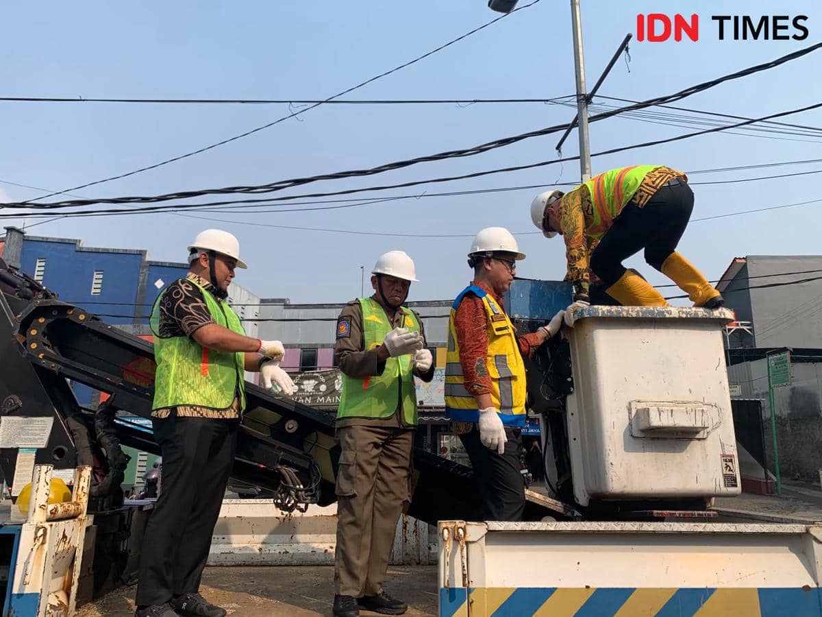 Petugas Pemkot Tangerang Selatan memotong kabel utilitas ilegal yang menjuntai di kawasan perkotaan.