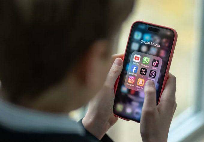 Seseorang sedang memgang smartphone yang menampilkan berbagai macam ikon media sosial.