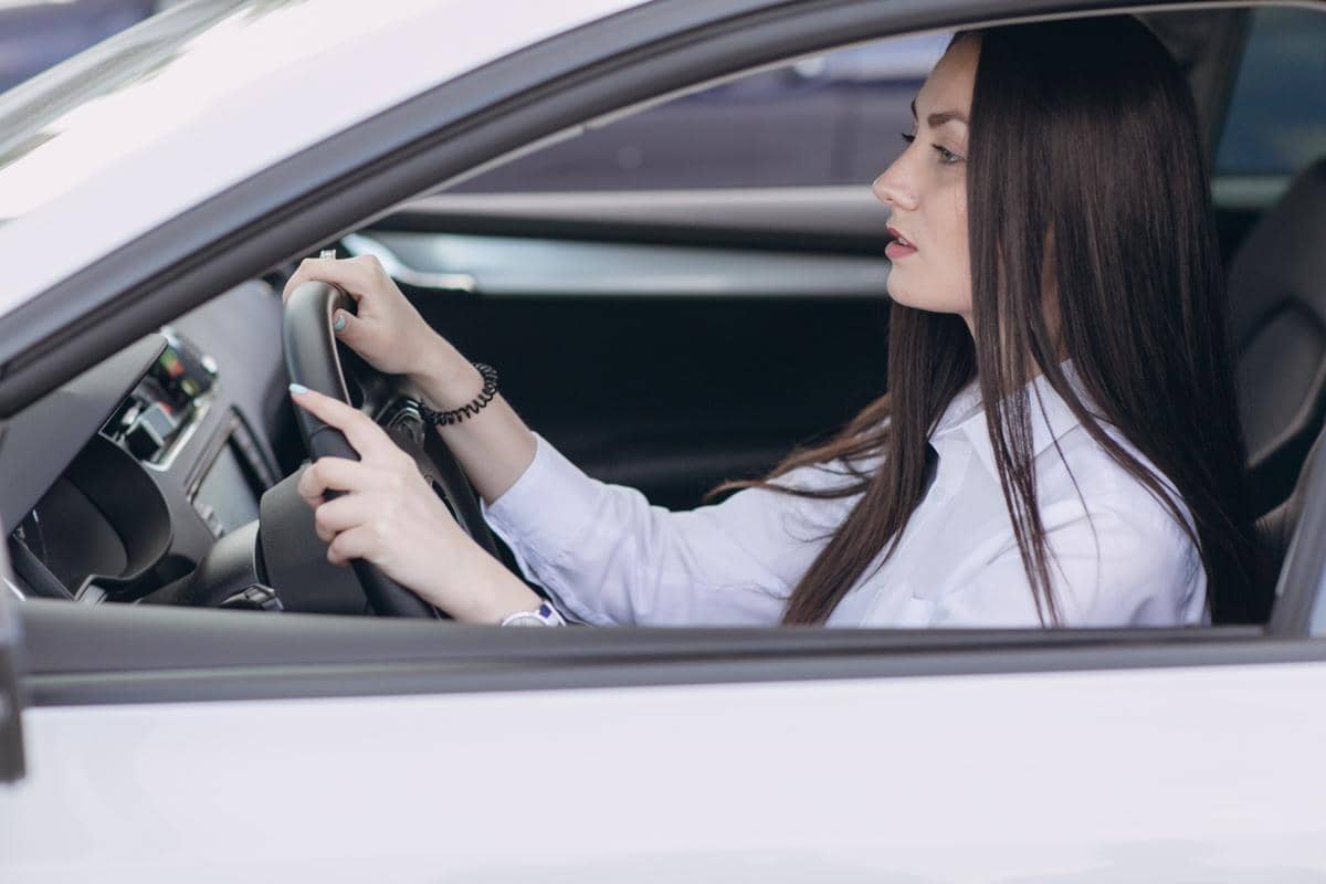 Seorang perempuan mengemudikan mobil di tengah kemacetan lalu lintas, terlihat dari dalam kabin kendaraan.