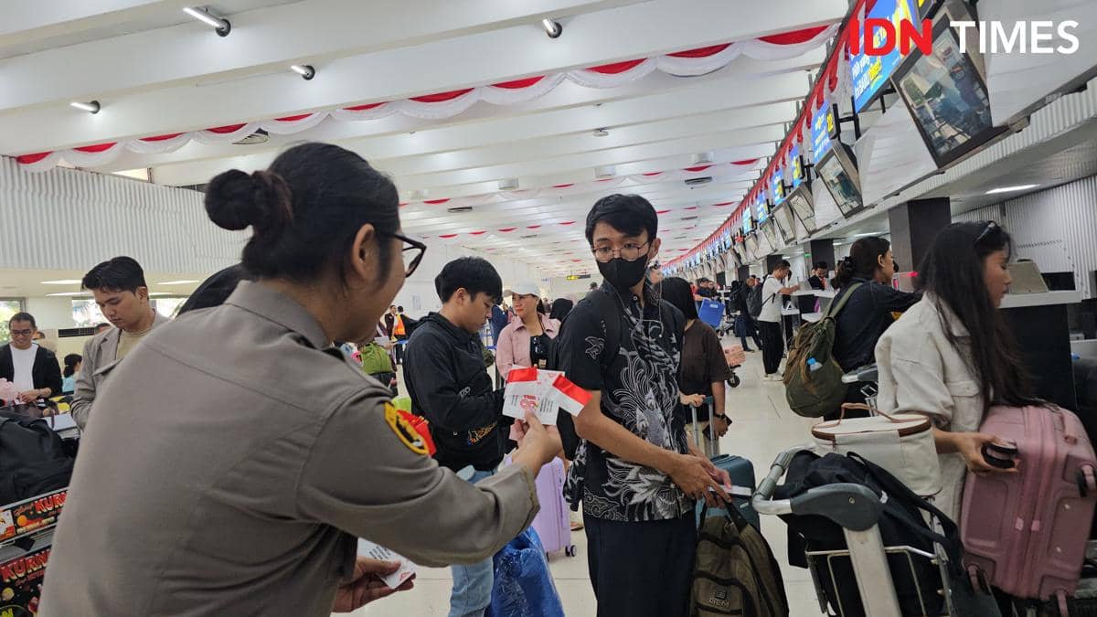 Petugas Polresta Bandara Soekarno-Hatta membagikan bendera Merah Putih kepada penumpang di area bandara.