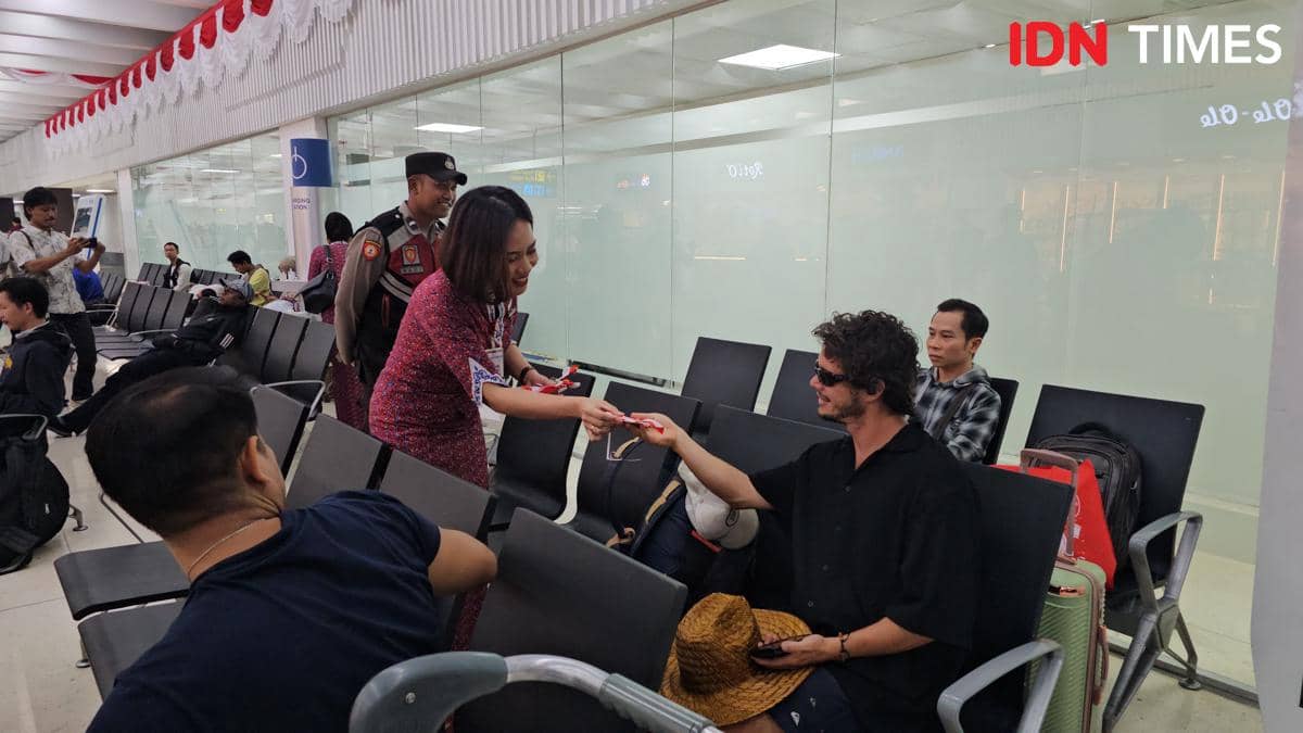 David, warga negara Australia, tersenyum sambil menerima cinderamata bendera Merah Putih di Bandara Soekarno-Hatta.