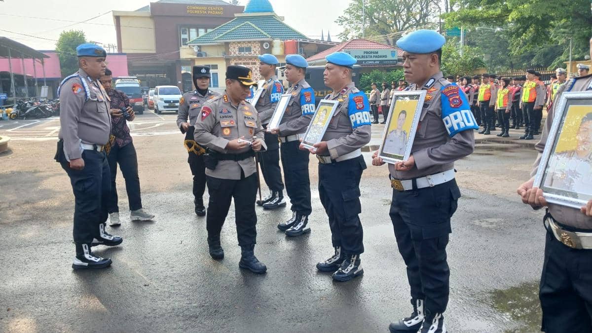 Kapolresta Padang berseragam mencoret nama personel yang dipecat pada papan daftar di hadapan peserta upacara.