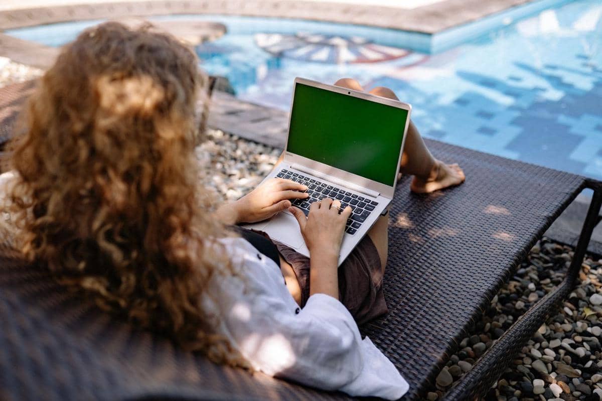 Ilustrasi pekerja remote menggunakan laptop di meja kerja, menggambarkan konsep digital nomad dan WFH.