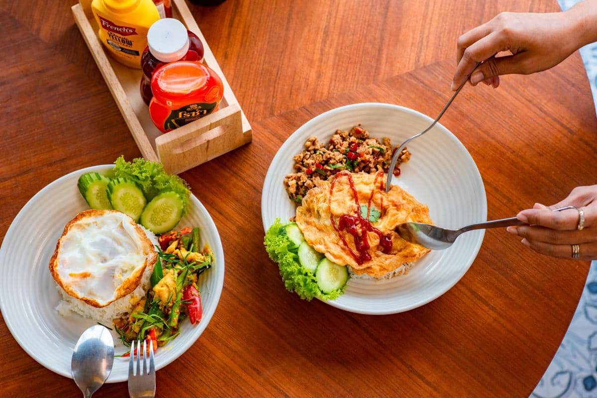 Ilustrasi seseorang duduk di meja makan dengan ekspresi siap menikmati hidangan yang telah tersaji di hadapannya.