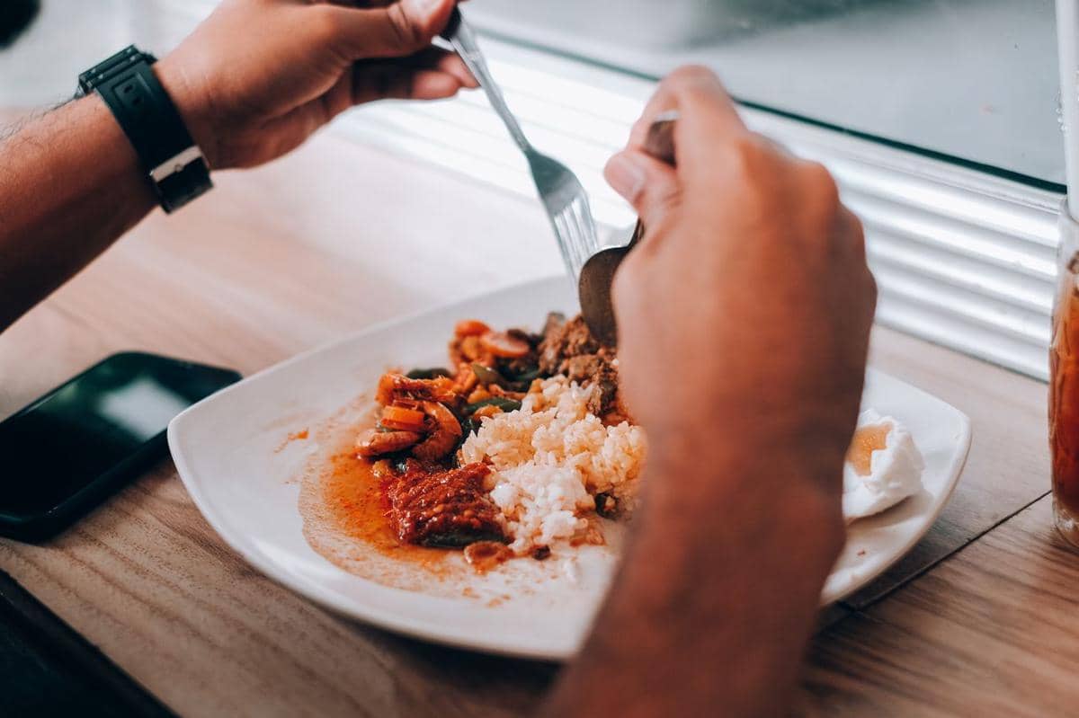 Ilustrasi seseorang menikmati makanan dengan suasana bersantap yang menyenangkan di meja makan.