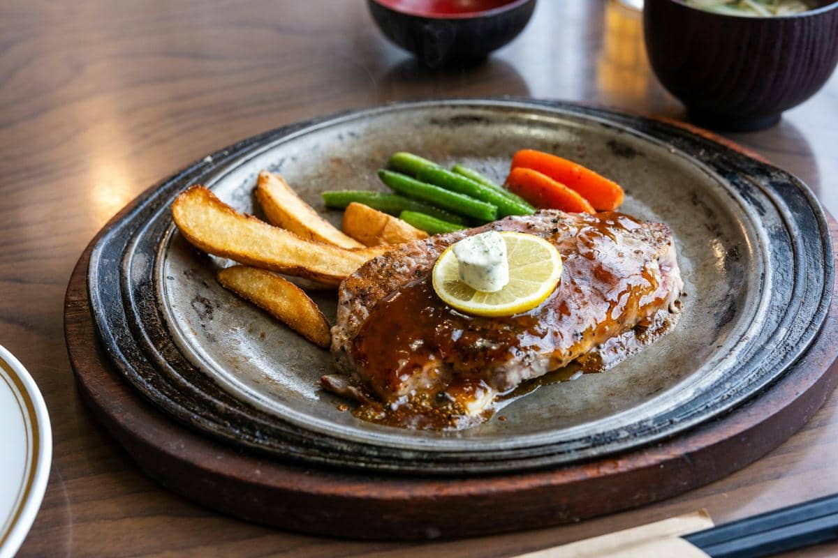 Steak tuna panggang berlapis saus salmoriglio, disajikan di atas piring sebagai ilustrasi hidangan laut.