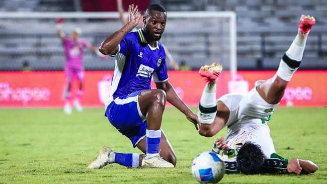 Duel pemain Persib Bandung dan Persebaya Surabaya dalam perebutan bola di tengah pertandingan.