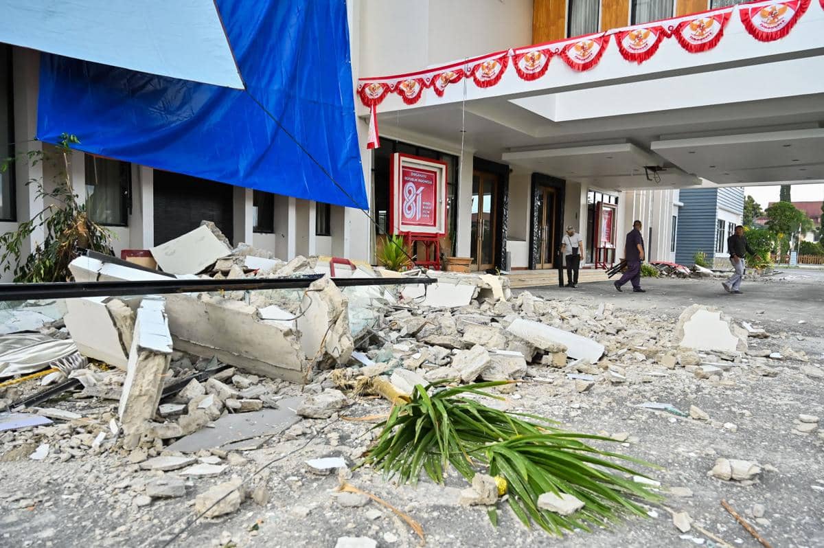 Pekerja berjalan di dekat bangunan Kantor Bupati Manggarai yang mengalami kerusakan akibat gempa di Kabupaten Manggarai, NTT, Minggu (16/8)