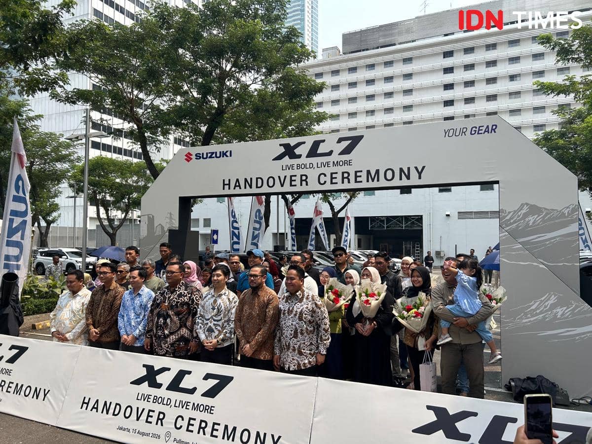 Konsumen pertama berpose di samping unit New XL7 berwarna putih dalam acara penyerahan kendaraan.