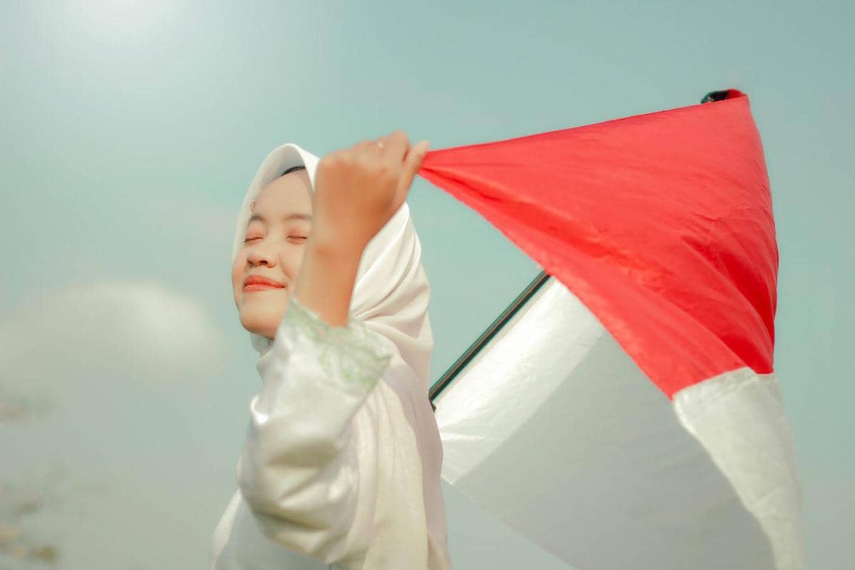 Warga membawa bendera Merah Putih dalam semangat Bulan Kemerdekaan