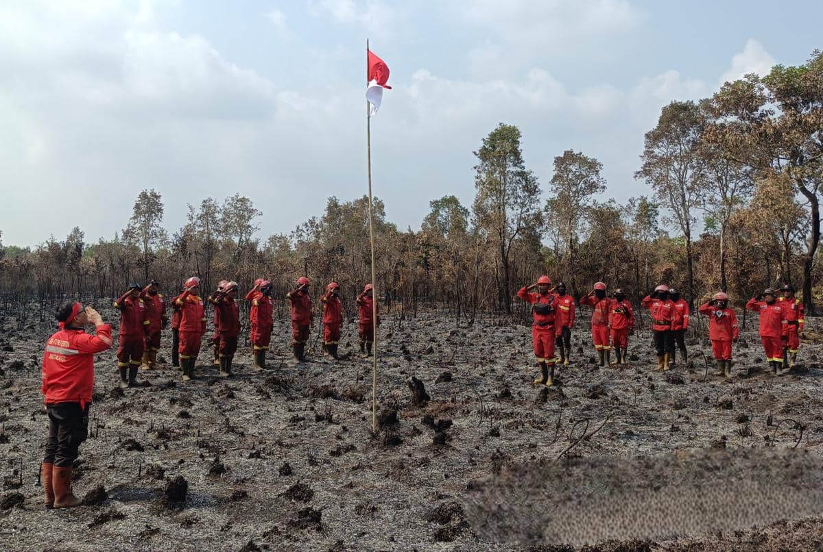 Tim Manggala Agni saat menggelar upacara bendera di tengah lahan terbakar di Desa Sungai Rambutan, Kabupaten Ogan Ilir, Sumatra Selatan, Senin (17/8/2026). 