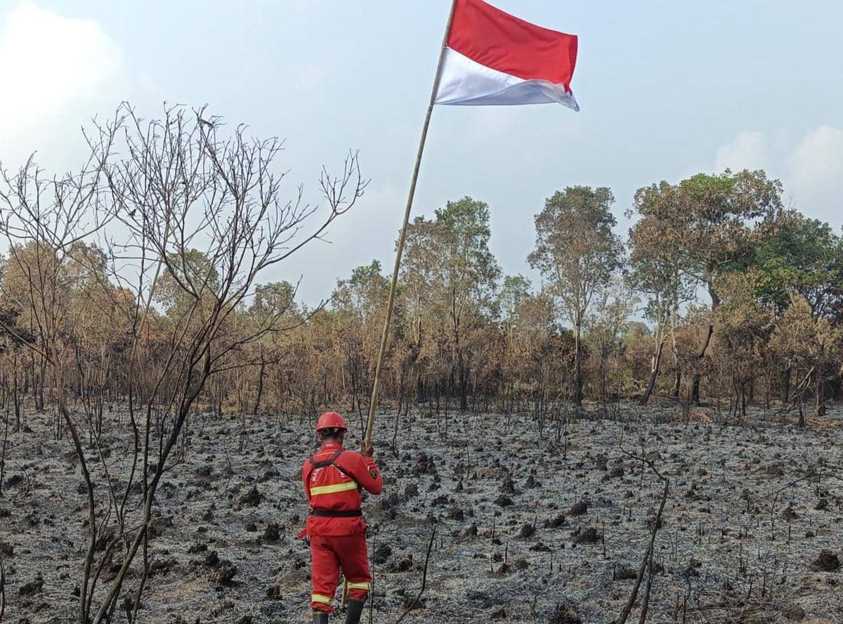 Tim Manggala Agni saat menggelar upacara bendera di tengah lahan terbakar di Desa Sungai Rambutan, Kabupaten Ogan Ilir, Sumatra Selatan, Senin (17/8/2026).