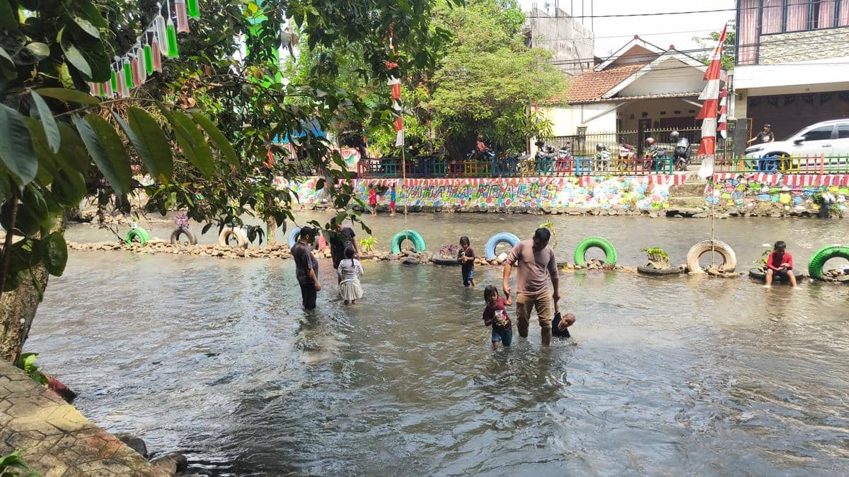 Aktivitas wisata pengunjung berlangsung di anak Sungai Ciliwung, kawasan Katulampa, Bogor, di tengah aliran air.