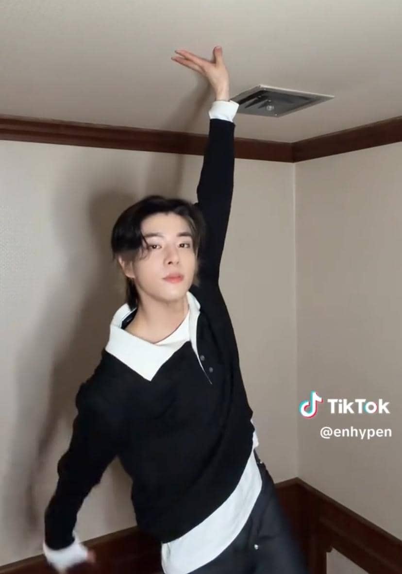 Jake, anggota grup K-pop ENHYPEN, tampil dalam potret dengan rambut gelap dan mengenakan atasan berwarna gelap.