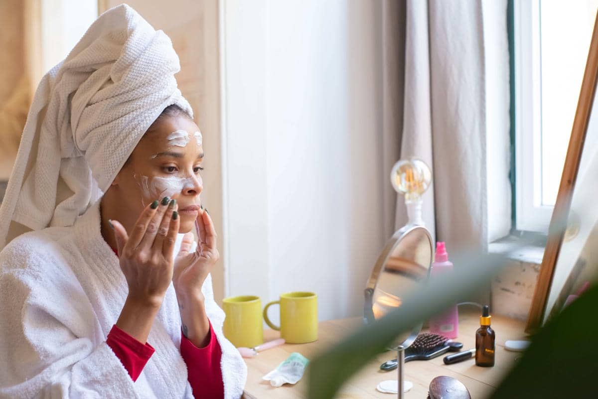 Seorang perempuan mengaplikasikan sunscreen pada wajah sebagai bagian dari rutinitas perawatan kulit harian.