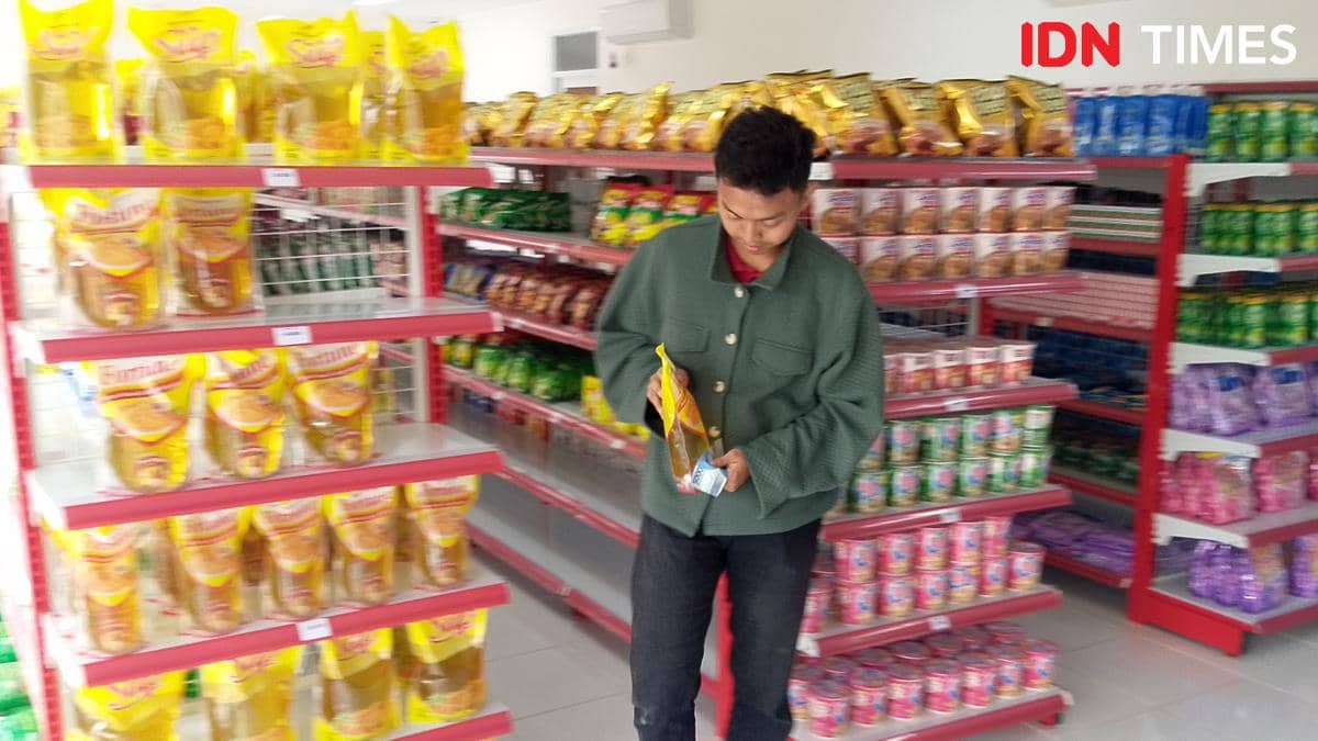 Seorang warga Margasana membeli minyak goreng, salah satu stok kebutuhan harian yang laris bersama beras.