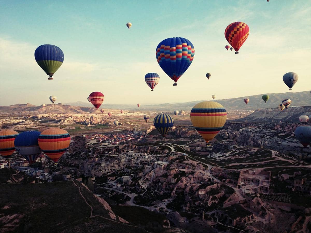 Pemandangan Cappadocia, Turki, memperlihatkan formasi batuan alami khas di bawah langit biru cerah.