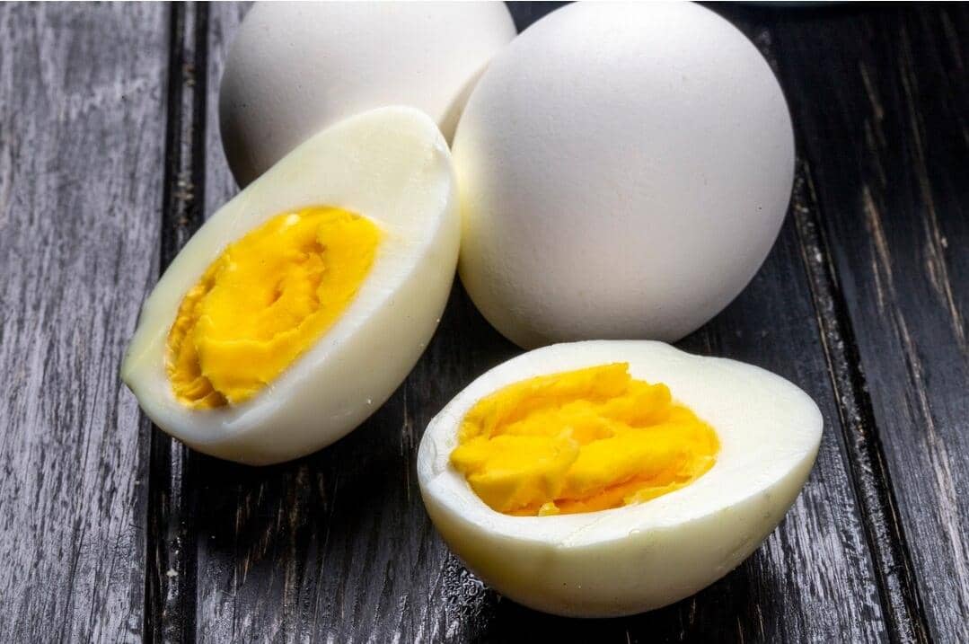 Ilustrasi telur rebus dengan cangkang putih, sebagian utuh dan sebagian dibelah untuk memperlihatkan kuning telur.
