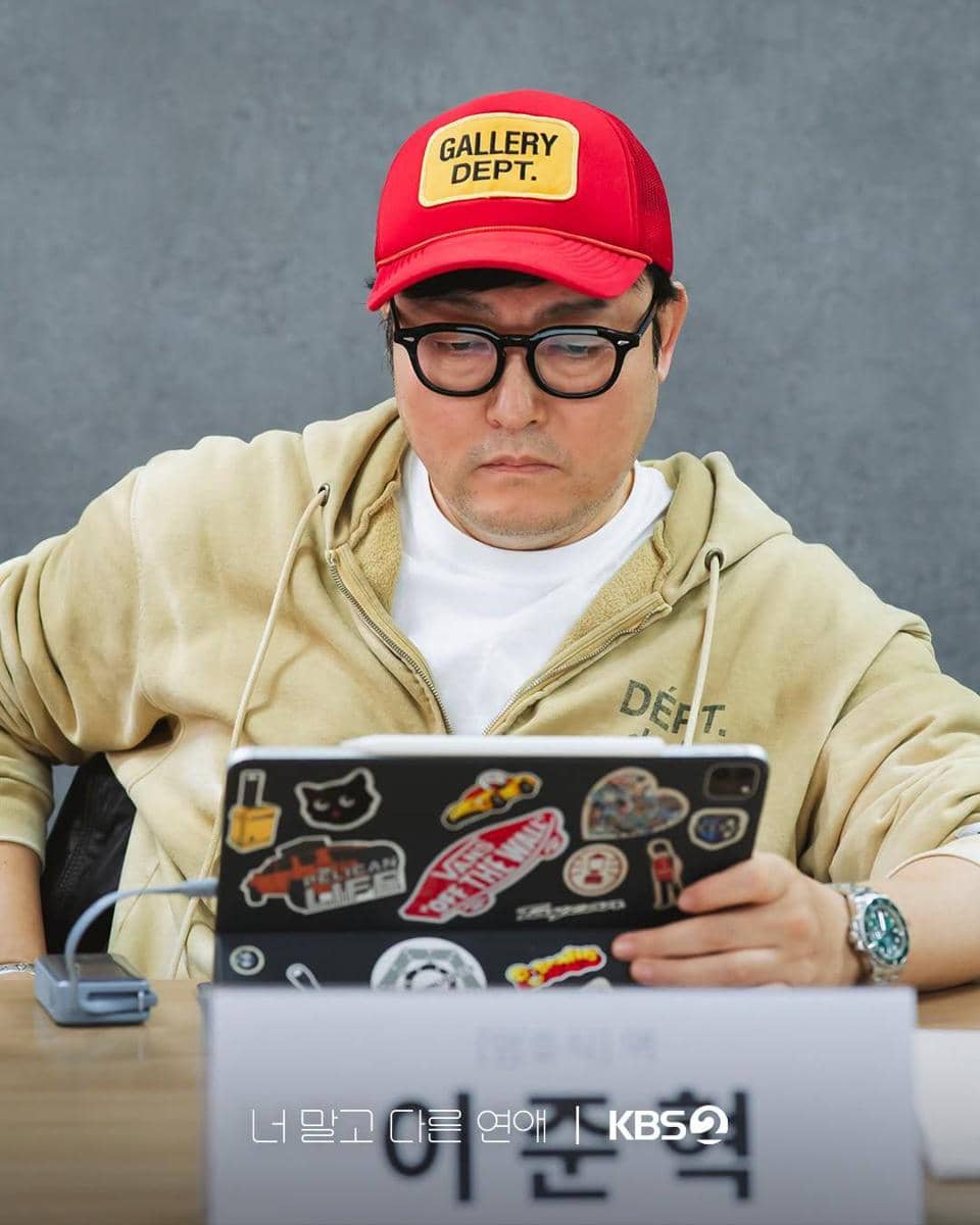 Lee Joon Hyuk mengenakan kemeja biru duduk membaca naskah drama A Love Other Than Yours di acara pembacaan naskah.