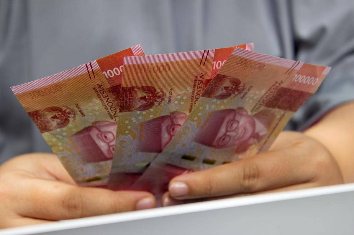 ilustrasi seseorang yang memegang beberapa uang kertas rupiah Indonesia