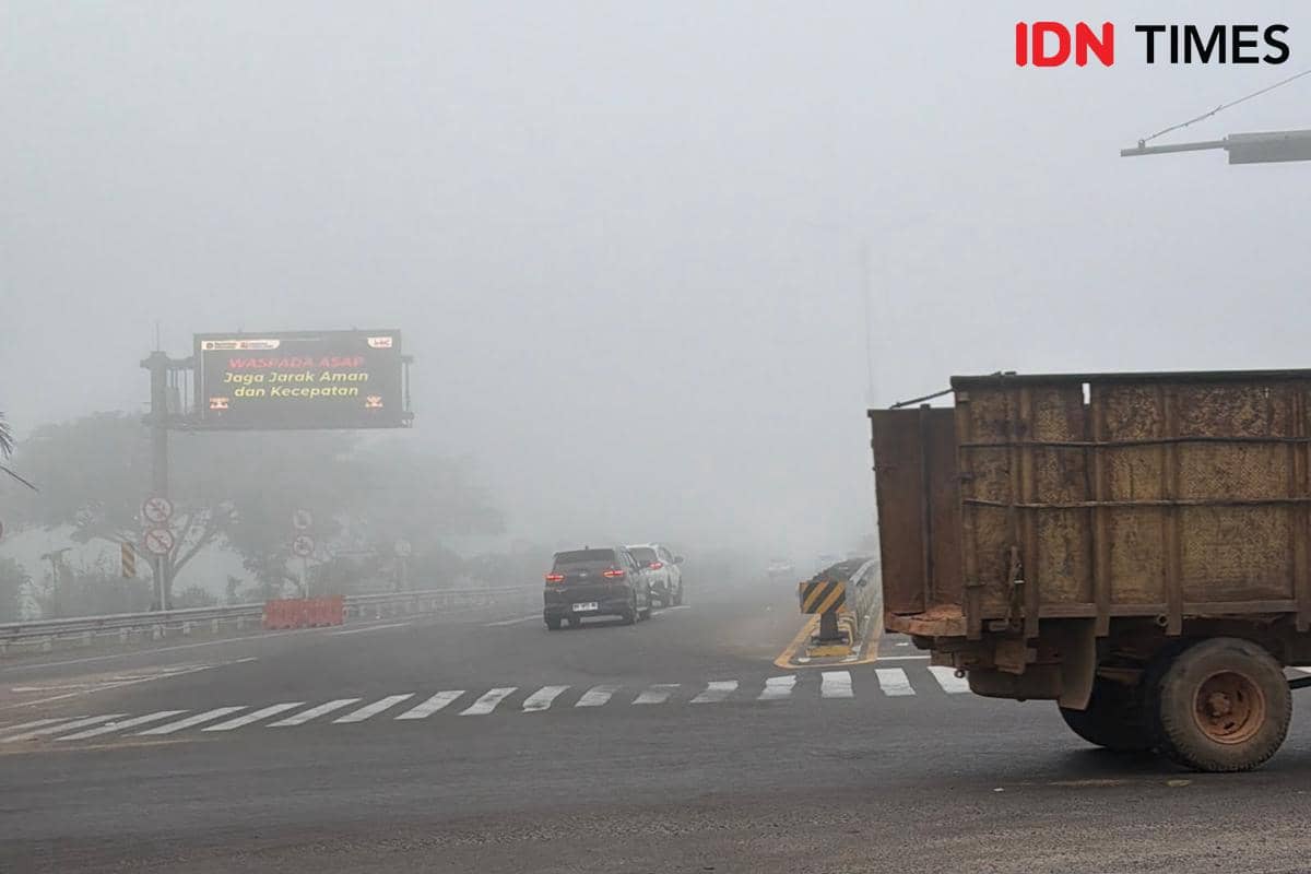 Kabut asap pekat menyelimuti kawasan Keramasan di Palembang, mengaburkan jalan akses menuju Tol Palembang-Indralaya.