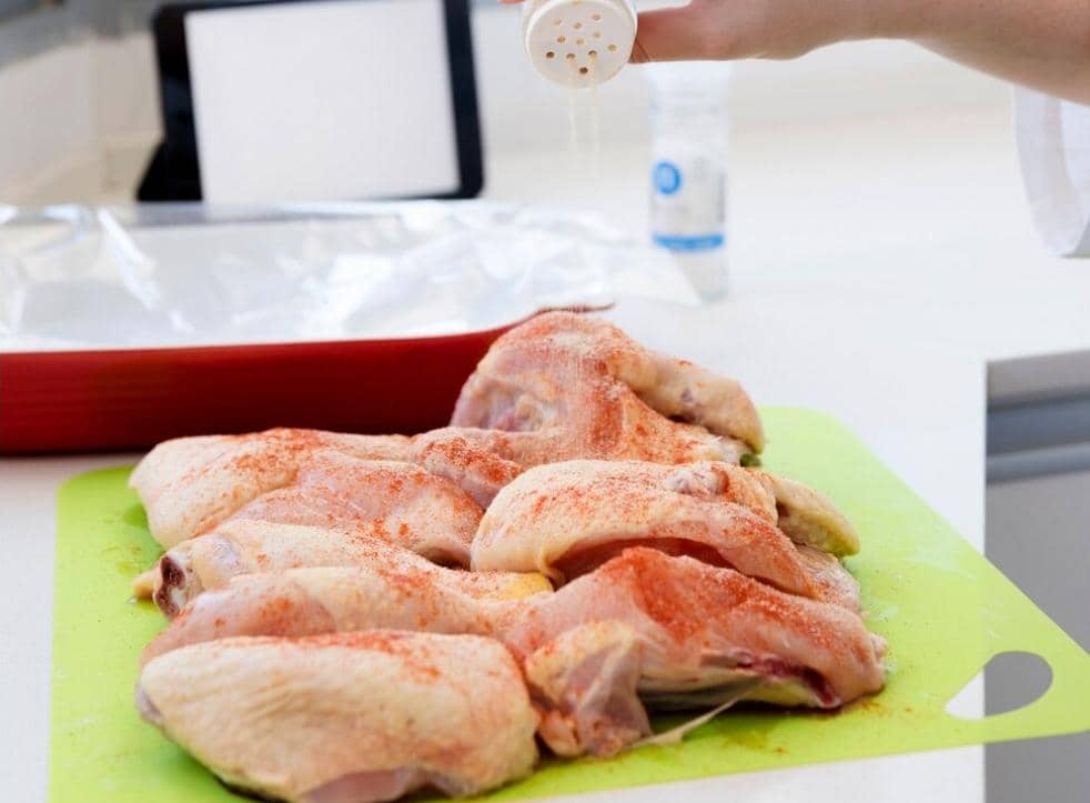 Ilustrasi potongan ayam mentah dalam wadah yang sedang dimarinasi dengan aneka bumbu sebelum dimasak.
