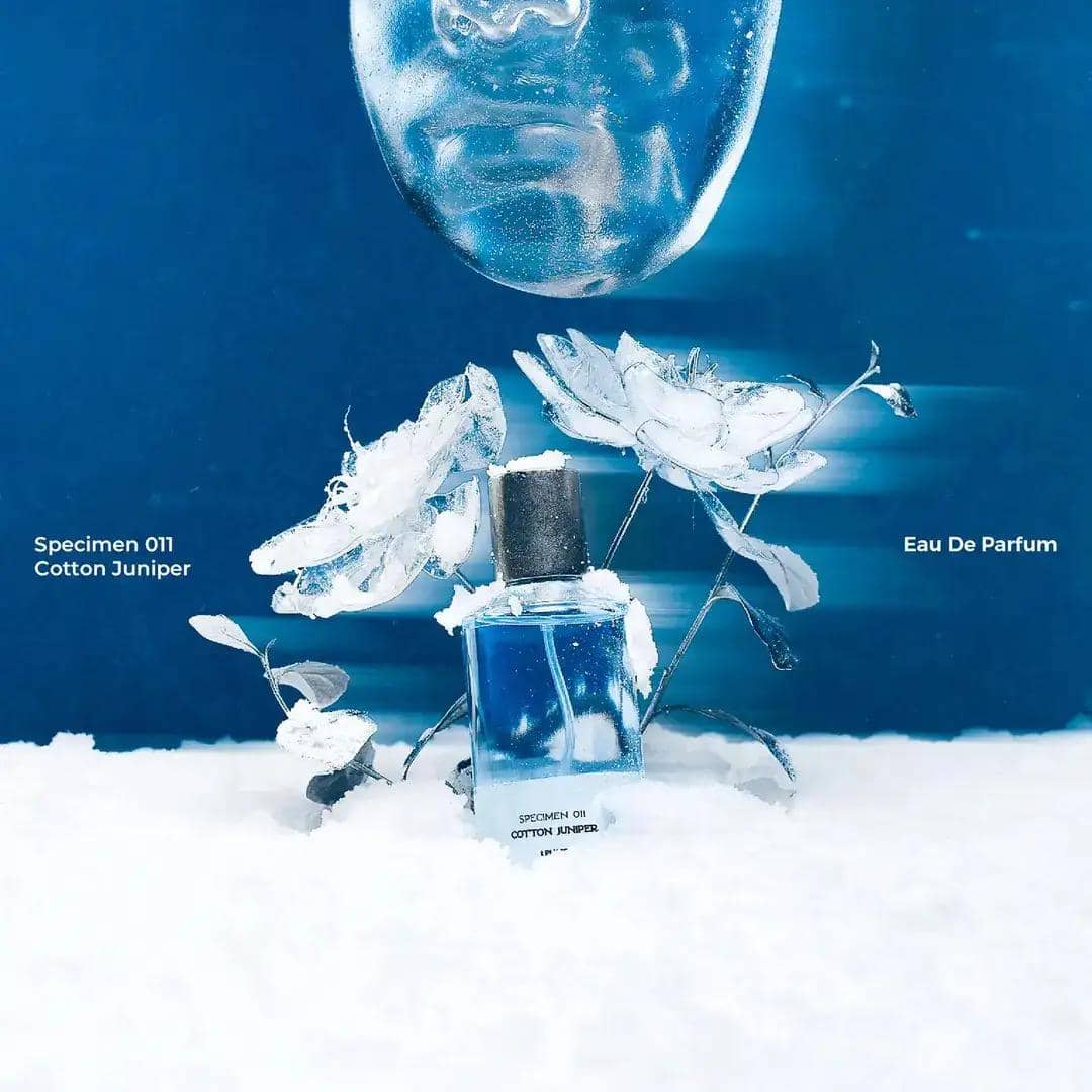 Botol parfum Scents of Pluto varian Cotton Juniper berwarna putih dengan desain minimalis di atas latar abu-abu.